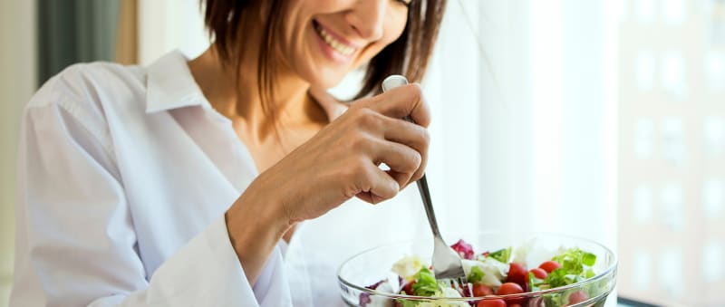 Woman smiling eating a salad with a fork