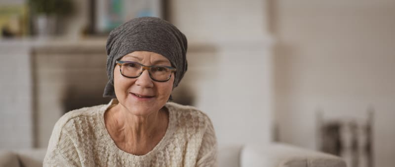 Woman at home wearing a dark grey head scarf and glasses
