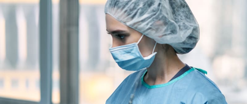 Surgeon in operating room wearing surgical mask and hair net