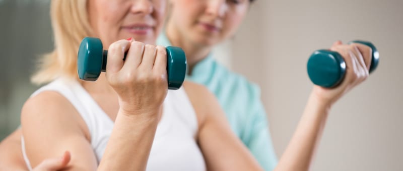 Woman with a personal trainer holding dumbells